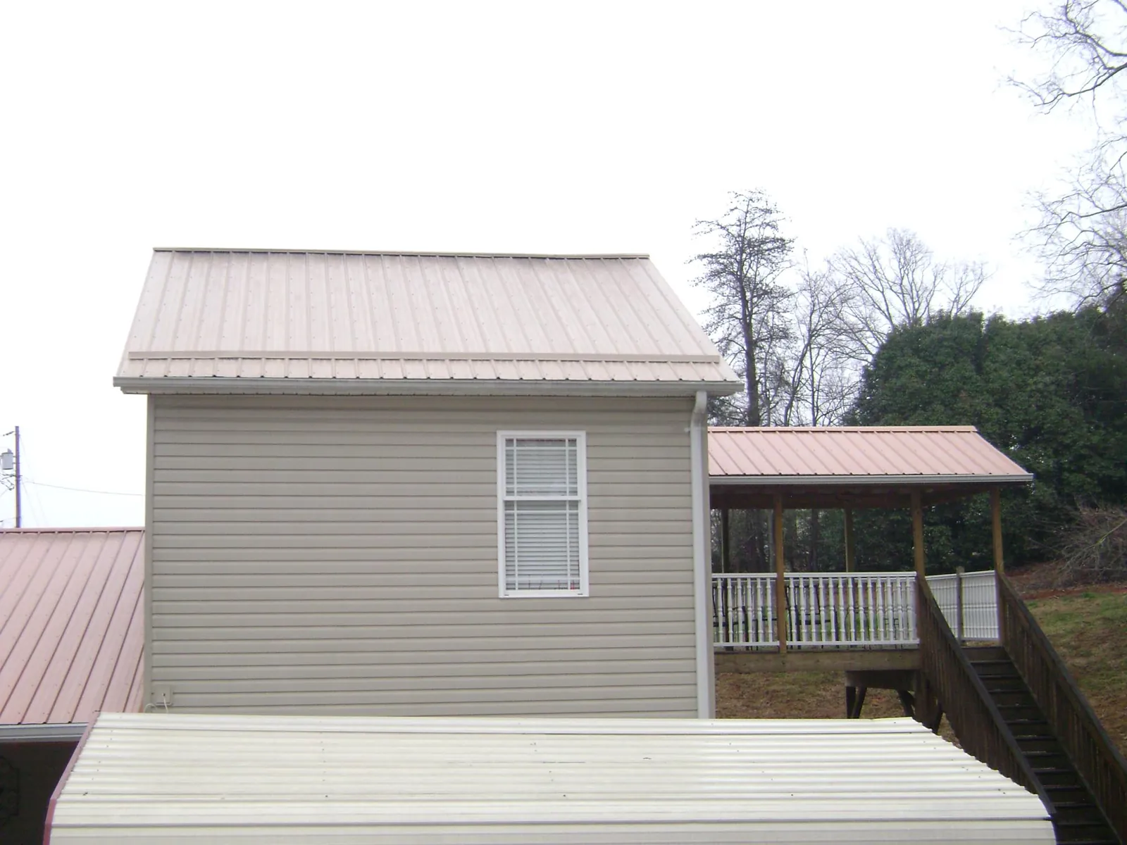 Tan metal roofs on a two story addition and attached porch in Russellville